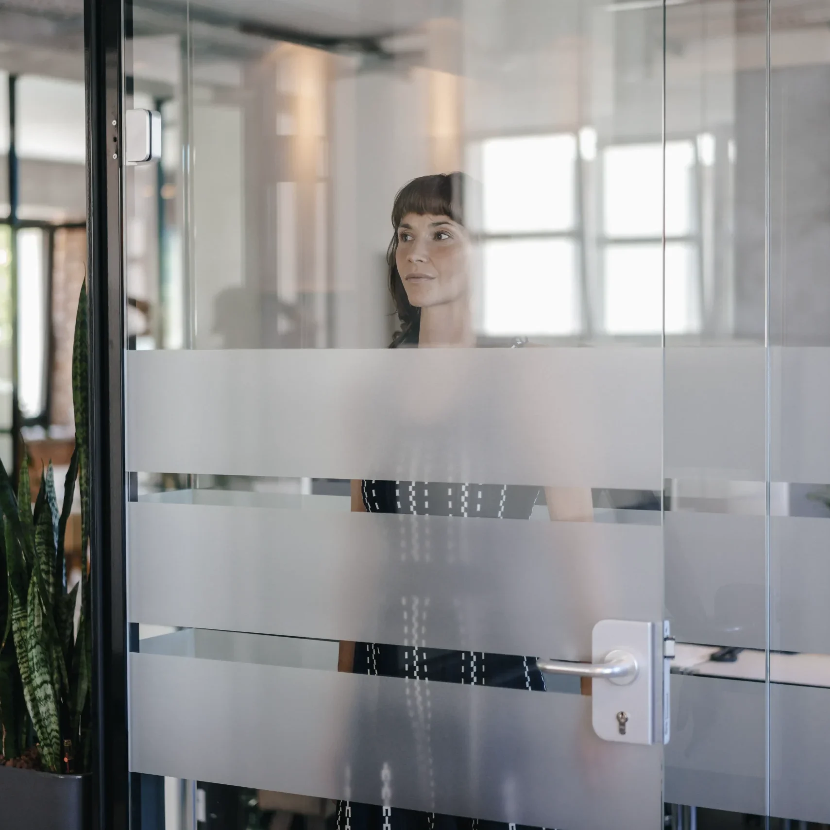 Mujer en oficina detrás de puerta de cristal.